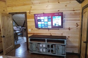 Ein an einer Holzwand befestigter Fernseher zeigt verschiedene Streaming-Dienste und einen Filmtitel.