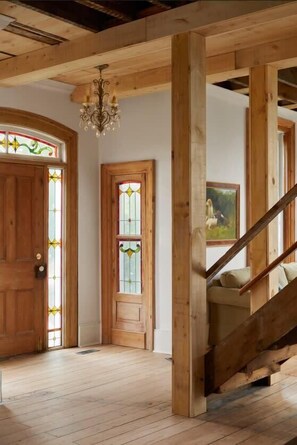 Een houten interieur met een trap, houten balken en een kroonluchter.
