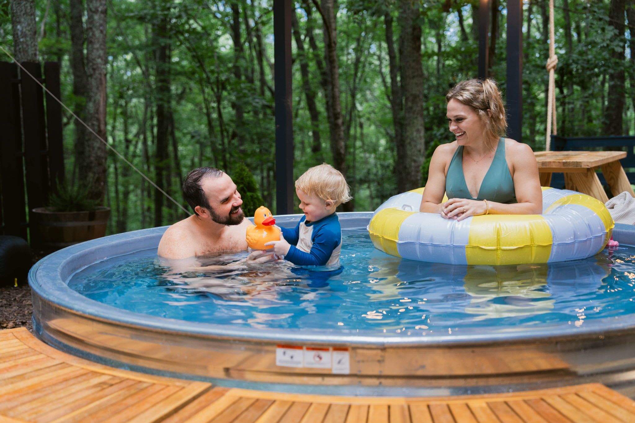 En swimmingpool med en træterrasse hele vejen rundt.
