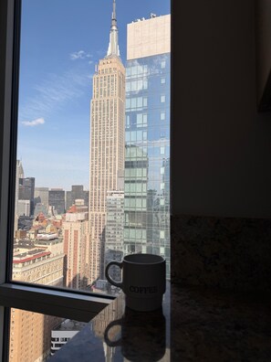 Una taza sobre un alféizar con vistas a un edificio alto y al paisaje urbano.