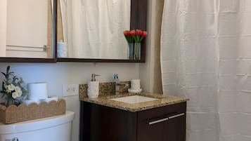 Un baño con inodoro, lavabo, espejo y cortina de ducha.