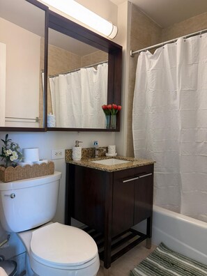 Un baño con inodoro, lavabo, espejo y cortina de ducha.