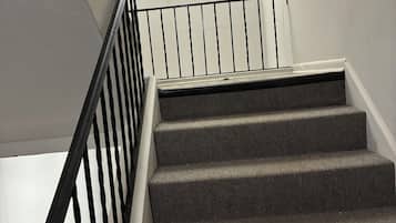 A staircase with a black metal railing and a fire extinguisher mounted on the wall.