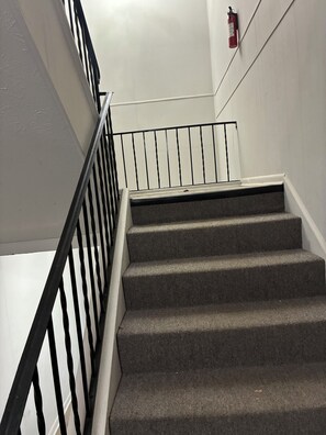 A staircase with a black metal railing and a fire extinguisher mounted on the wall. - Lovely, Modern 1-bedroom condo with Balcony, AC in serene Atlanta neighborhood (Atlanta)