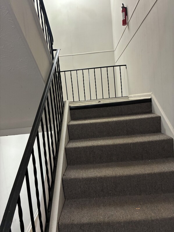 A staircase with a black metal railing and a fire extinguisher mounted on the wall.