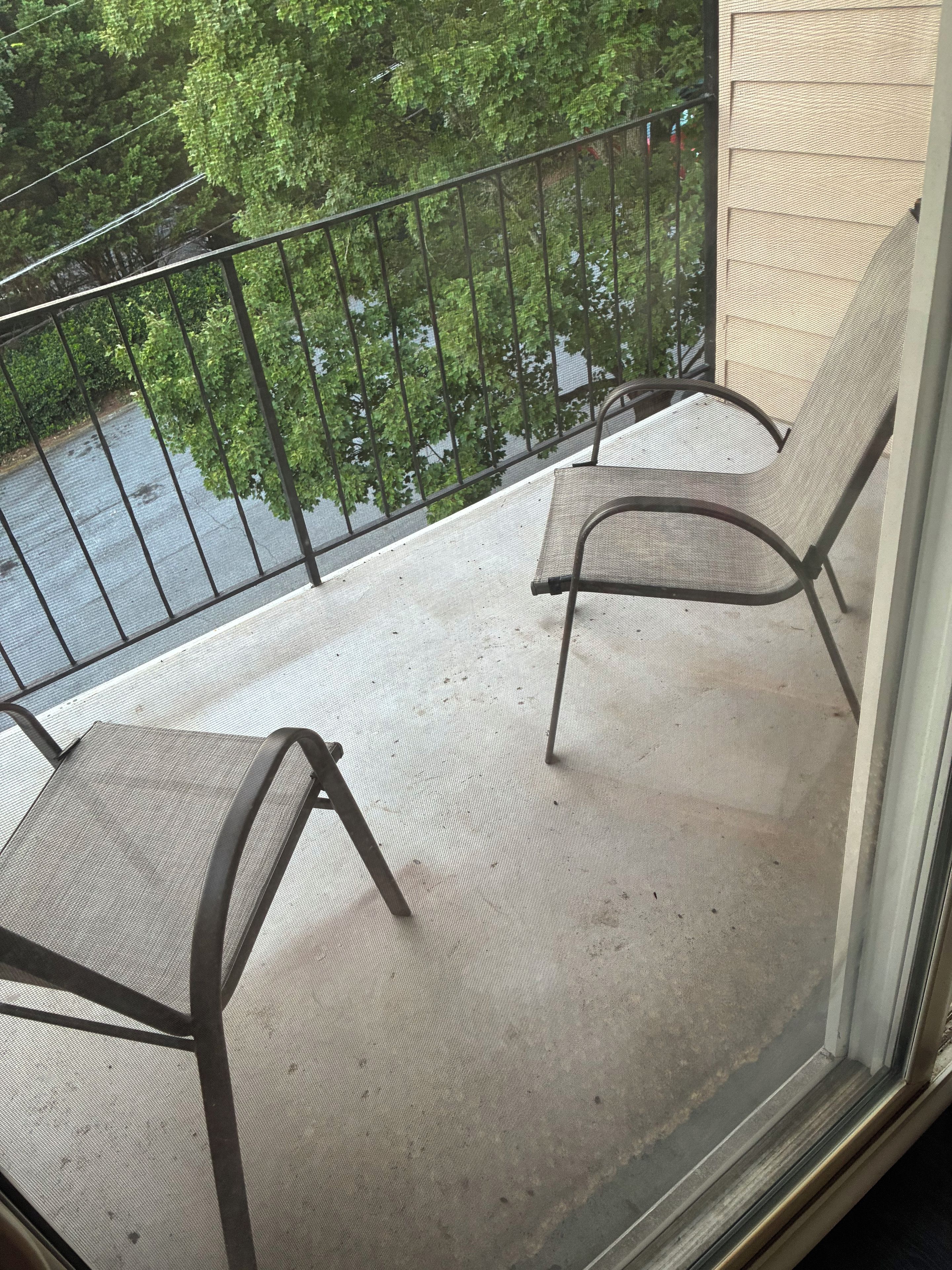 A balcony with two chairs and a metal railing.