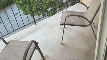 A balcony with two chairs and a metal railing.