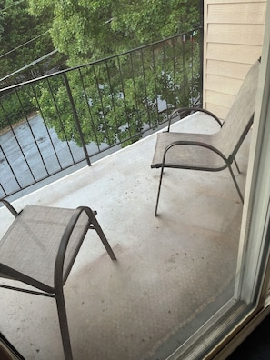 A balcony with two chairs and a metal railing.