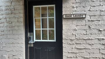 A black door with a window, a 'Guest Laundry' sign, and a textured wall.