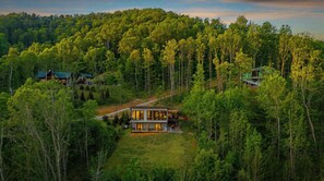 Uma casa moderna de dois andares rodeada por uma floresta densa.