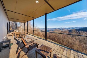 Eine überdachte Terrasse im Freien mit Holzmöbeln und Blick auf Berge.