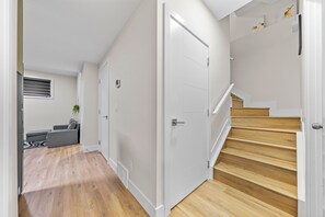 A modern interior with a staircase, a living area with a sofa, and a door leading to another room. - 2BHK Close to Downtown/Whyte Ave/UOFA 10633 (Edmonton)
