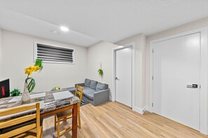 Ein zeitgemäßer Wohnraum mit Essbereich, einem grauen Sofa und einer weißen Tür.