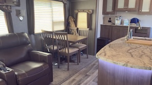 Un intérieur de camping-car compact comprenant un coin repas, un coin salon et une kitchenette.