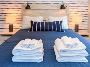 A hotel room with a bed, two pillows, two bedside lamps, and two stacks of folded towels. - Lakefront - Kids' Hangout - Fire Pit - Kayaks (Barnstead)