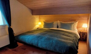 Une chambre à coucher avec un lit, deux lampes de chevet et une fenêtre avec des rideaux.