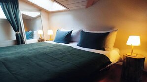 Une chambre d’hôtel avec un lit, deux lampes de chevet, une fenêtre avec des rideaux et un miroir au mur.