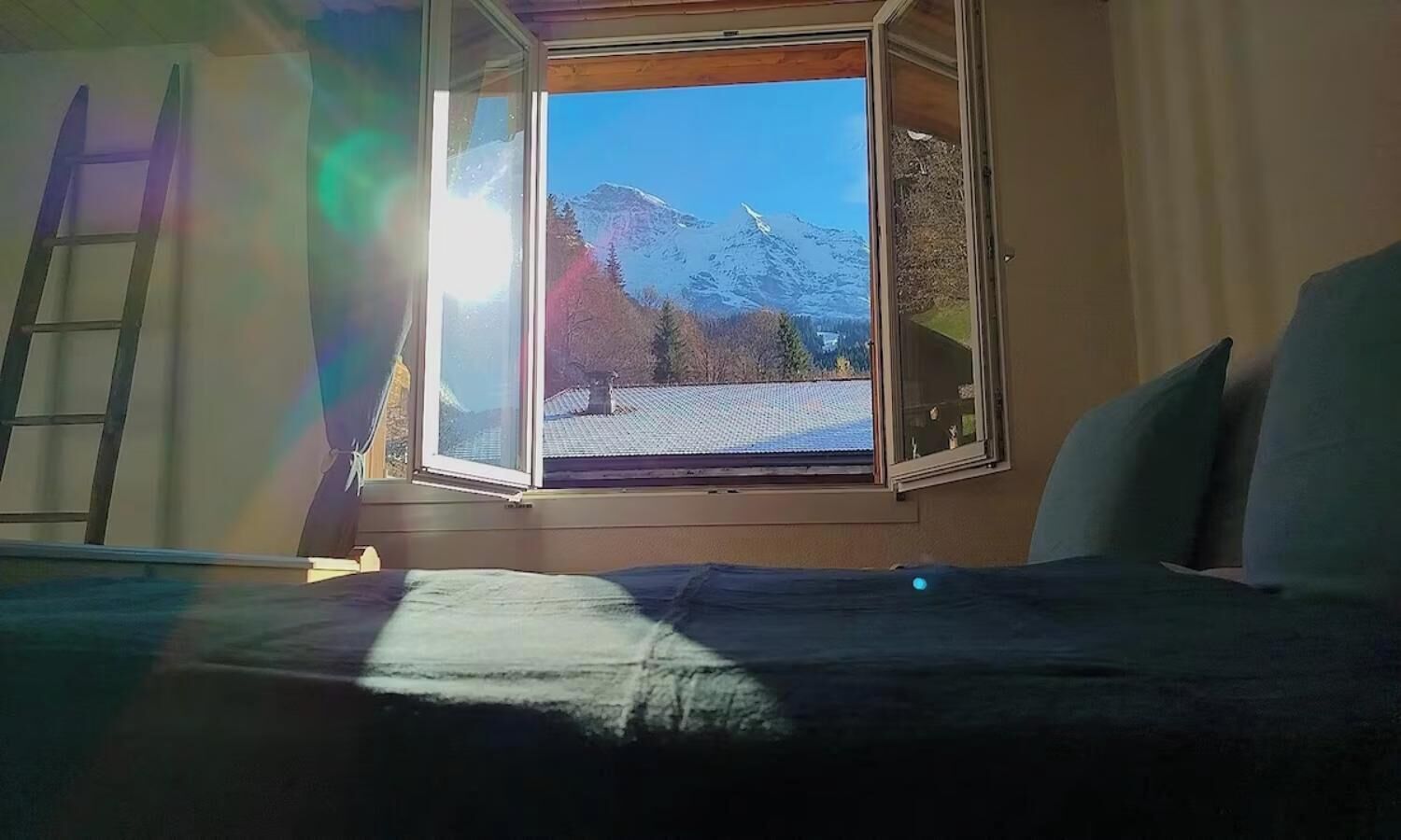 Une pièce avec un lit, une fenêtre et une échelle.