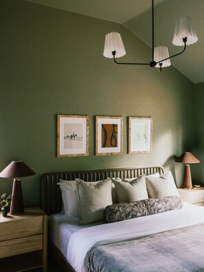 Un dormitorio con cama, mesitas de noche, lámparas y decoración en la pared.