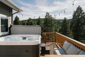 Un jacuzzi en una terraza con vistas a un área boscosa.