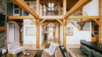 Um loft espaçoso com vigas de madeira aparentes, uma escada central e vista para a cozinha.
