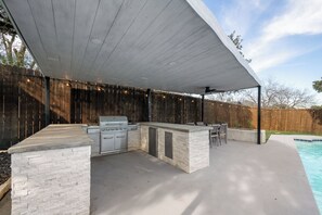 Ein Außenbereich mit Küche, inklusive Grill, Bar und Sitzgelegenheiten.