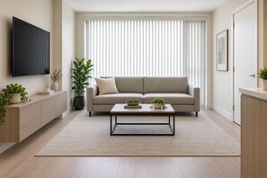 A living room with a sofa, a coffee table, a TV, and potted plants. - The Caleford Hotel (Toronto)