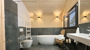Ein modernes Badezimmer mit einer freistehenden Badewanne, einer Toilette und einem Waschtisch mit Spiegel.