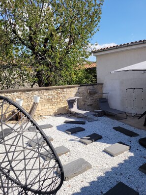 A patio area with a stone wall, a white building, and a tree. - Maison 3 chambres avec patio centre ville de Jonzac animaux acceptés (Jonzac)