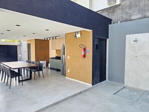 A modern kitchen with a built-in refrigerator, a dining area with a table and chairs, and a fire extinguisher mounted on the wall. - Atlantic Residence Carneiros (Tamandaré)