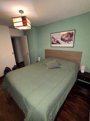 A bedroom with a bed, a nightstand, a wall-mounted lamp, and a framed picture. - Modern & Spacious Duplex in Montevideo | 3 Bedrooms, 2 Bathrooms, and Wi-Fi (Montevideo)