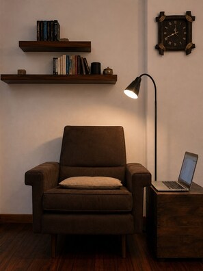 A room with a brown armchair, a wooden side table with a laptop, a wall-mounted clock, and two shelves with books and decorative items. - Modern & Spacious Duplex in Montevideo | 3 Bedrooms, 2 Bathrooms, and Wi-Fi (Montevideo)