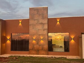 A modern building with a central stone pillar, large windows, and wall-mounted lighting. - Libre Hotel (Nova Ponte)