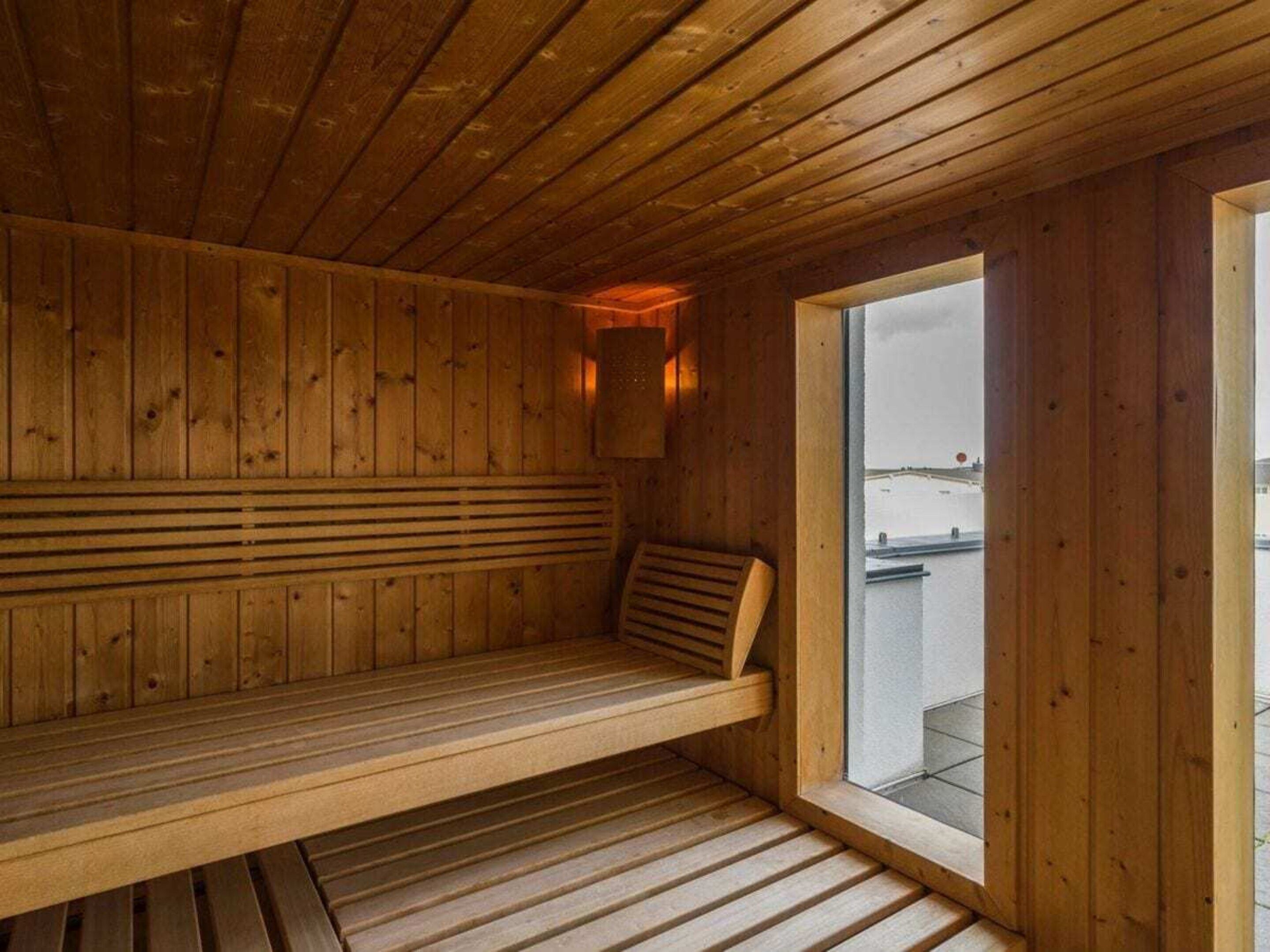 Eine Holzsauna mit einer Bank und einem Fenster mit Blick nach draußen.