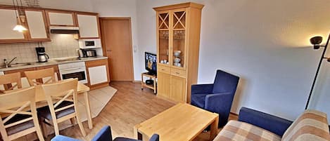 Espaço compacto com cozinha compacta, área de refeições e sala de estar com sofá e cadeiras.