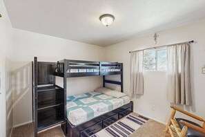 Une chambre avec un lit superposé, une fenêtre, des rideaux et une chaise.