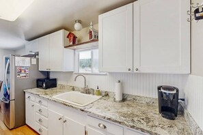 A kitchen with white cabinets, a granite countertop, a sink, a microwave, and a coffee maker. - Hummingbird Retreat | Mountain Views + Wolf Creek (South Fork)