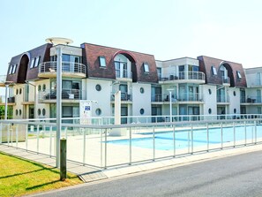 Ein modernes Mehrstöckiges Hotel mit Schwimmbad, Balkonen und einer Glasfassade.