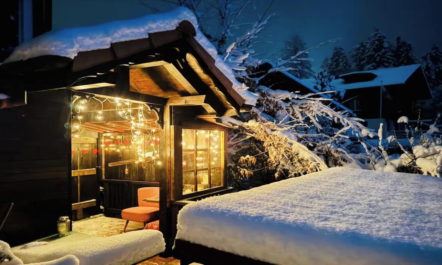 Un bâtiment en bois avec une façade en verre, un environnement enneigé et un banc à l’extérieur.