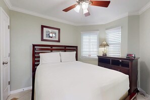 Une chambre à coucher avec un lit, une table de chevet, une lampe et un ventilateur de plafond.