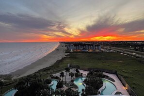 A resort with a pool area, beachfront, and a view of the ocean at sunset. - Diamond Beach Resort Penthouse (Galveston)