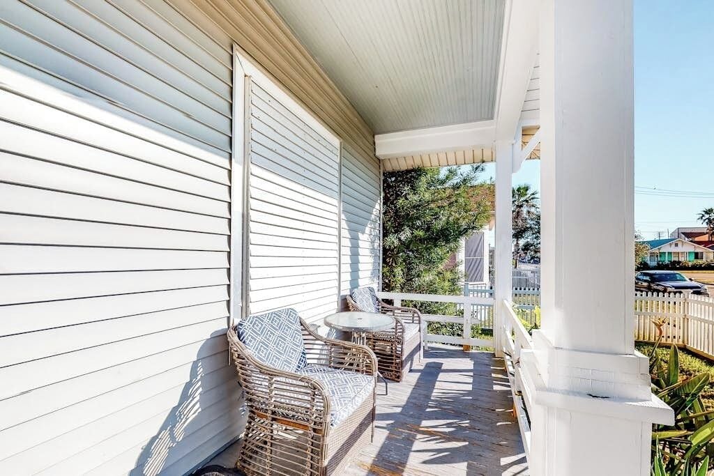 A covered porch with wicker furniture and a small table.