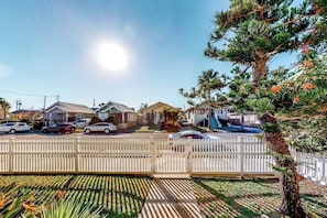 A residential street with houses, parked cars, and a white picket fence. - Castaway Cottage - Big Backyard & Dog-Friendly (Galveston)