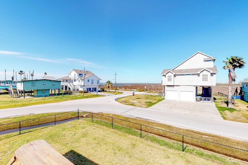 A residential area with houses, a road, and a fenced grassy area.