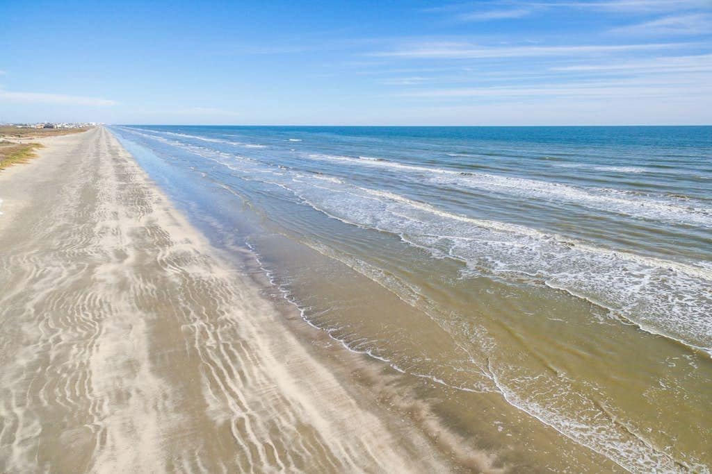 Una playa con un camino arenoso que lleva al océano.