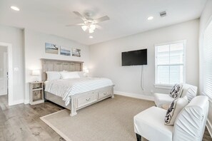 A bedroom with a bed, a chair, a television, and a ceiling fan. - Seaside Haven - Gulf Views, 2 Blocks to Beach (Galveston)