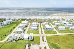 A coastal residential area with houses, a road, and a view of the ocean. - Seaside Haven - Gulf Views, 2 Blocks to Beach (Galveston)