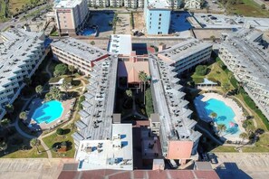 Ein Hotelkomplex mit mehreren Gebäuden, Schwimmbecken und einem Innenhof.