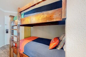 Ein Stockbett mit einer Holzleiter, einer blauen Matratze und einem gestreiften Kissen.