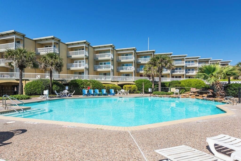 Ein Hotel mit Schwimmbad, mehreren Balkonen und Palmen.